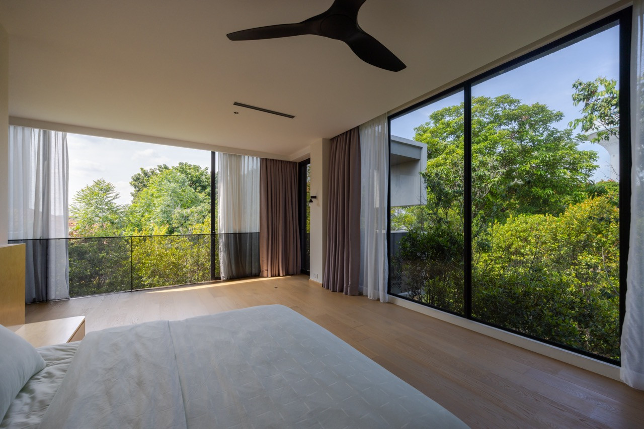 The grooved concrete feature wall of the double-volume living-dining hall rises the full height of the space, with views to the pool through floor-to-ceiling glazing