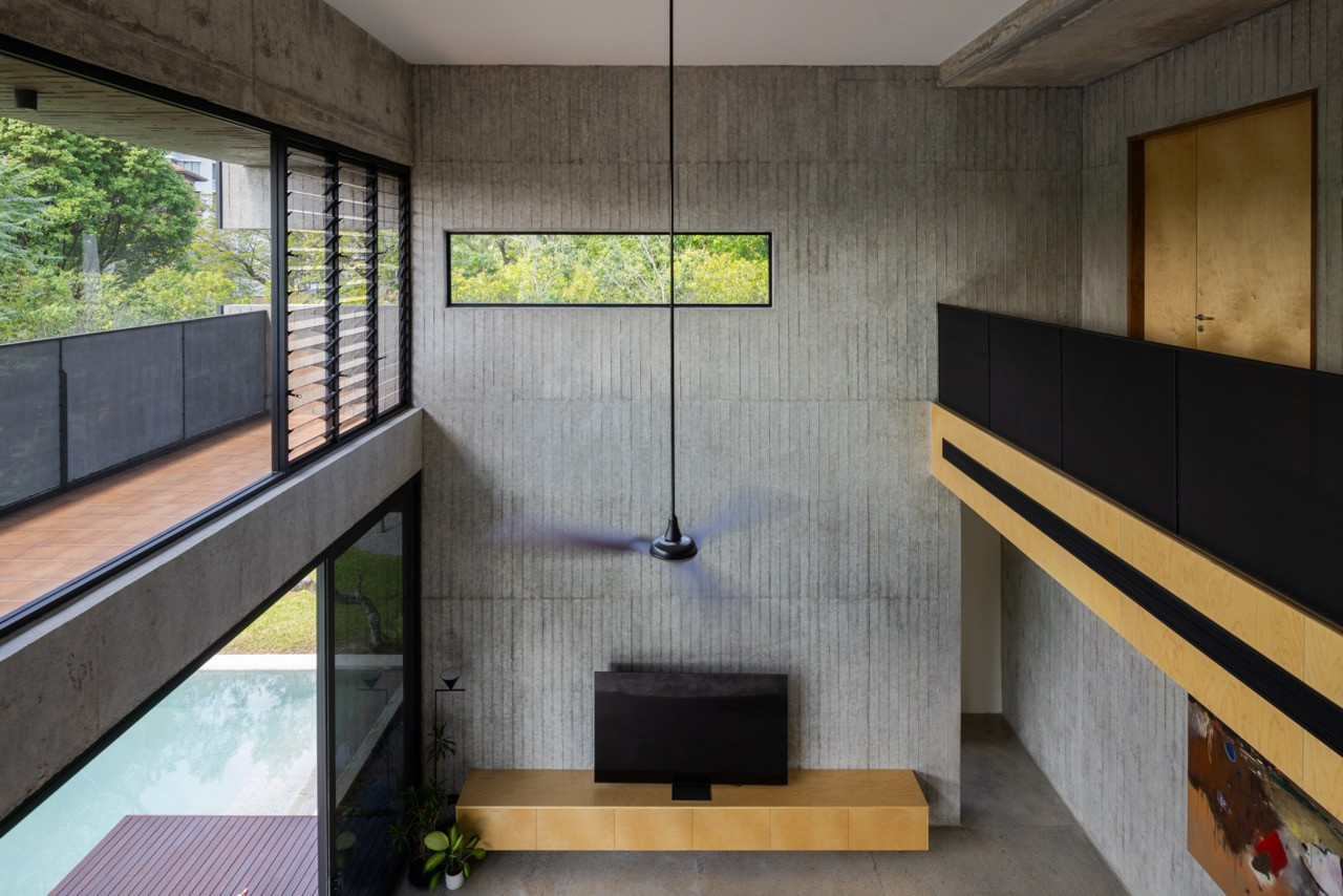 The grooved concrete feature wall of the double-volume living-dining hall rises the full height of the space, with views to the pool