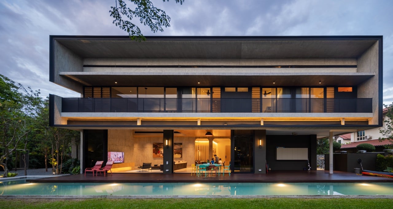 The rear facade opens fully to the pool deck and lawn, with the cantilevered upper volume providing shade to the ground-floor living spaces below