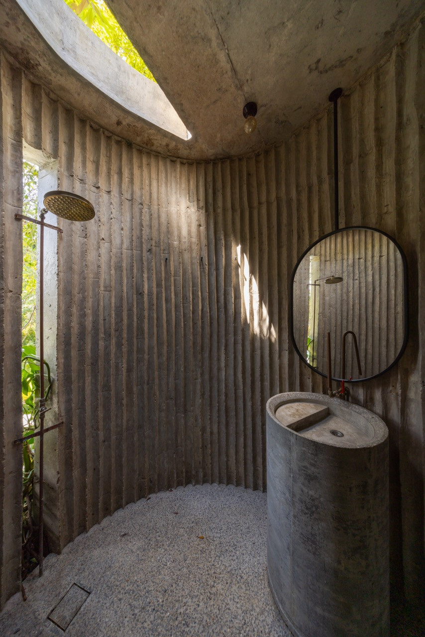 The interior of the powder room has a basin fashioned from a drain culvert and a curved skylight admitting natural light from above