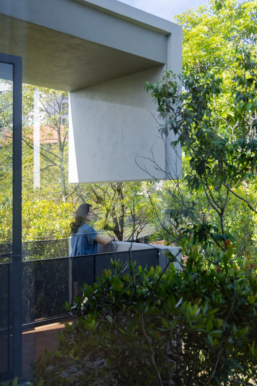 The cantilevered concrete volumes of the upper floor project into the garden, with the master balcony situated at the point of overlap between the two shifted masses
