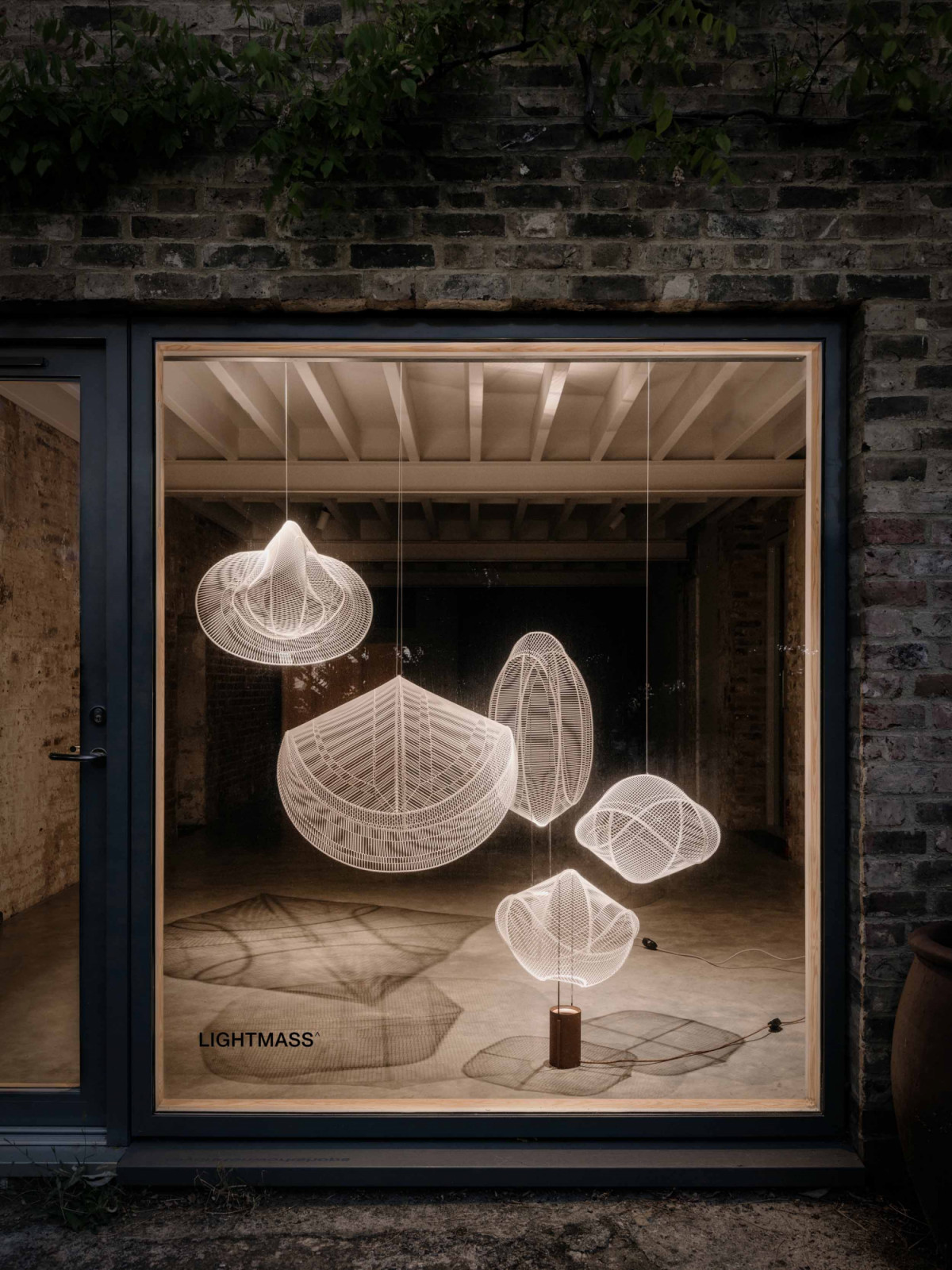 LightMass^, whose airy mesh forms direct a focused beam downward while casting atmospheric shadows