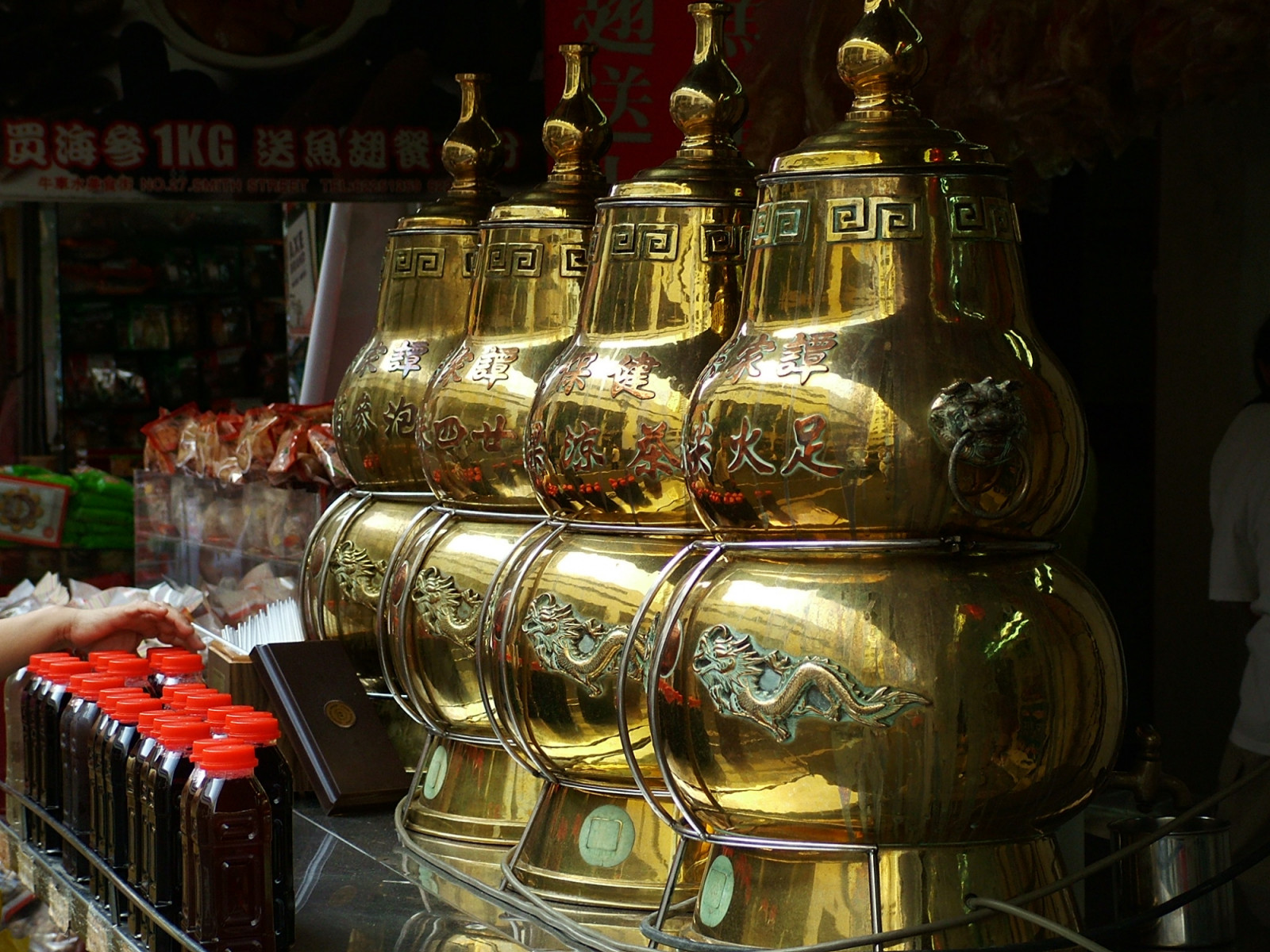 Ornate golden urns dispense traditional herbal tea, with pre-bottled selections available, at a street stall.