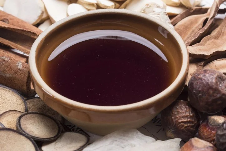 A dark herbal tea infusion, with botanicals including cinnamon bark and various dried roots.