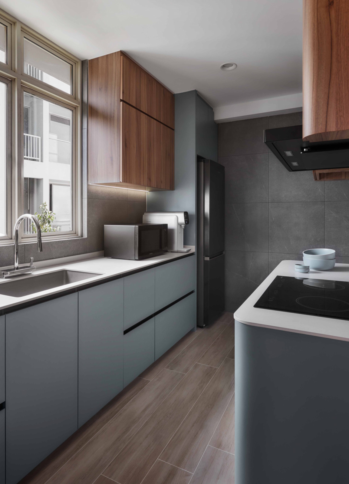 The kitchen balances sage-toned cabinetry with warm walnut overheads and a sleek black cooker hood