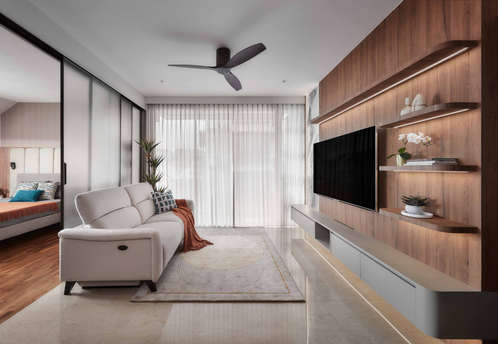 The living room opens onto the resting area through a frosted glass sliding door, softened by sheer curtains