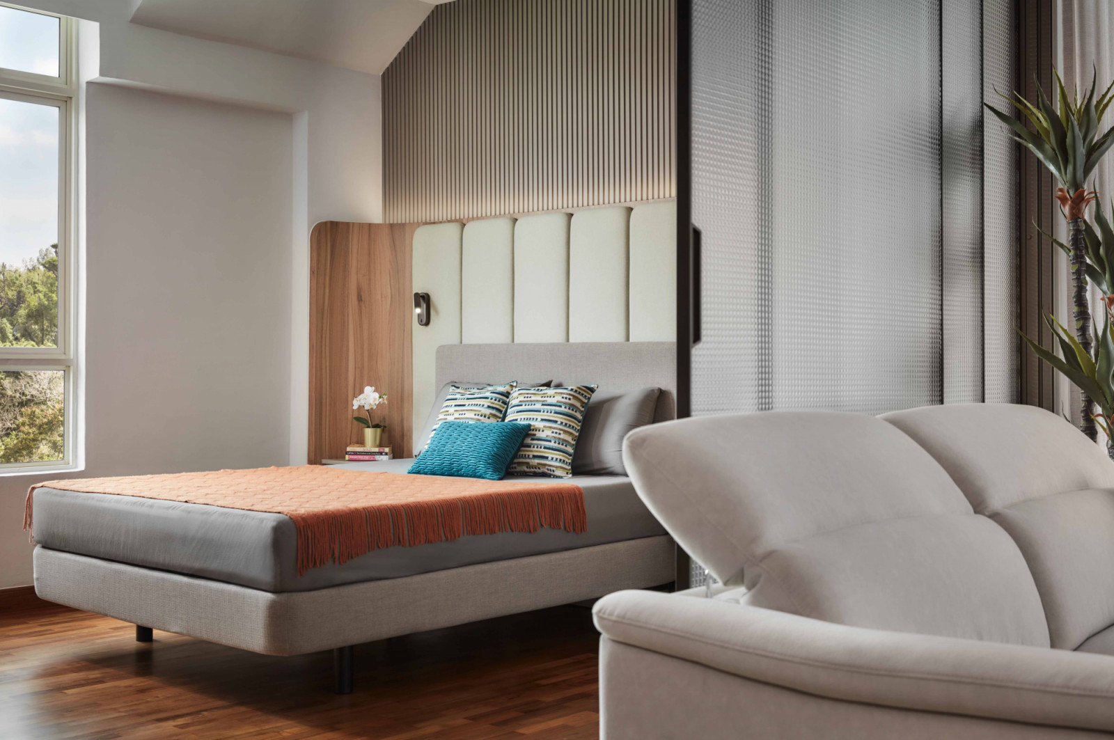 An orange fringed throw and reclining armchair bring a relaxed, hotel‑like warmth to this bedroom