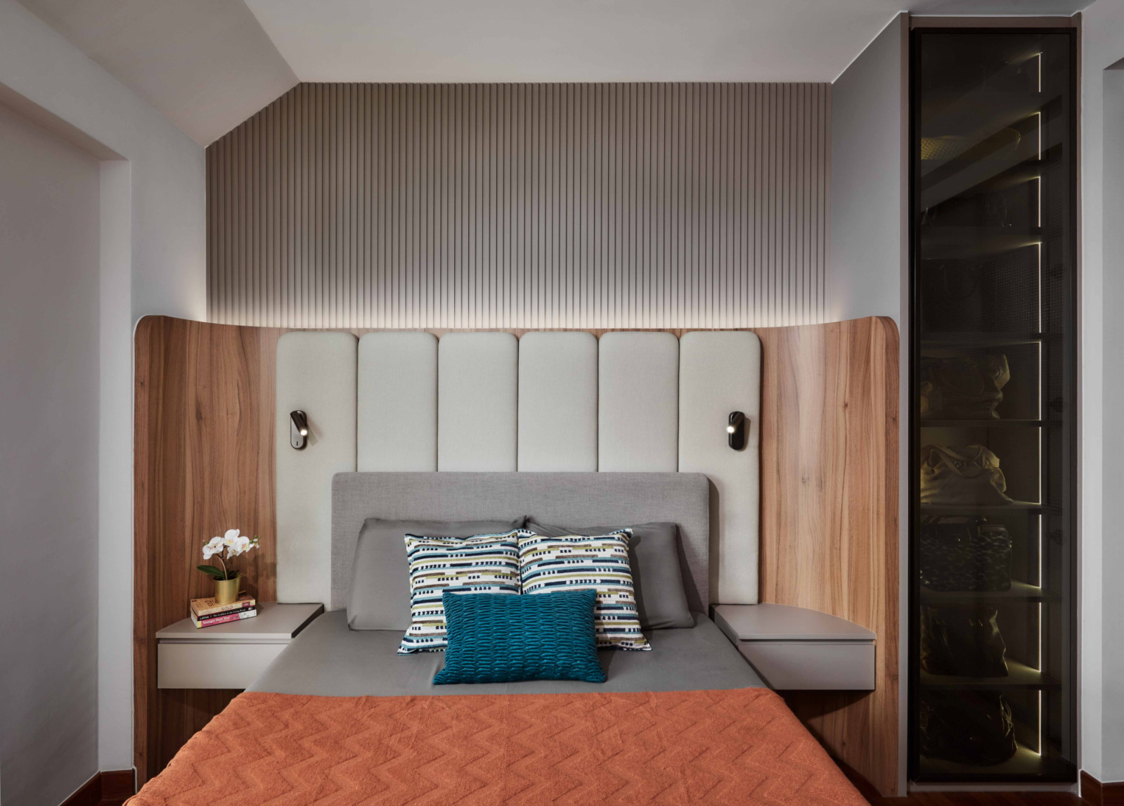 The master headboard’s upholstered panels and timber surround create a hotel‑suite feel, with a walk‑in wardrobe beyond