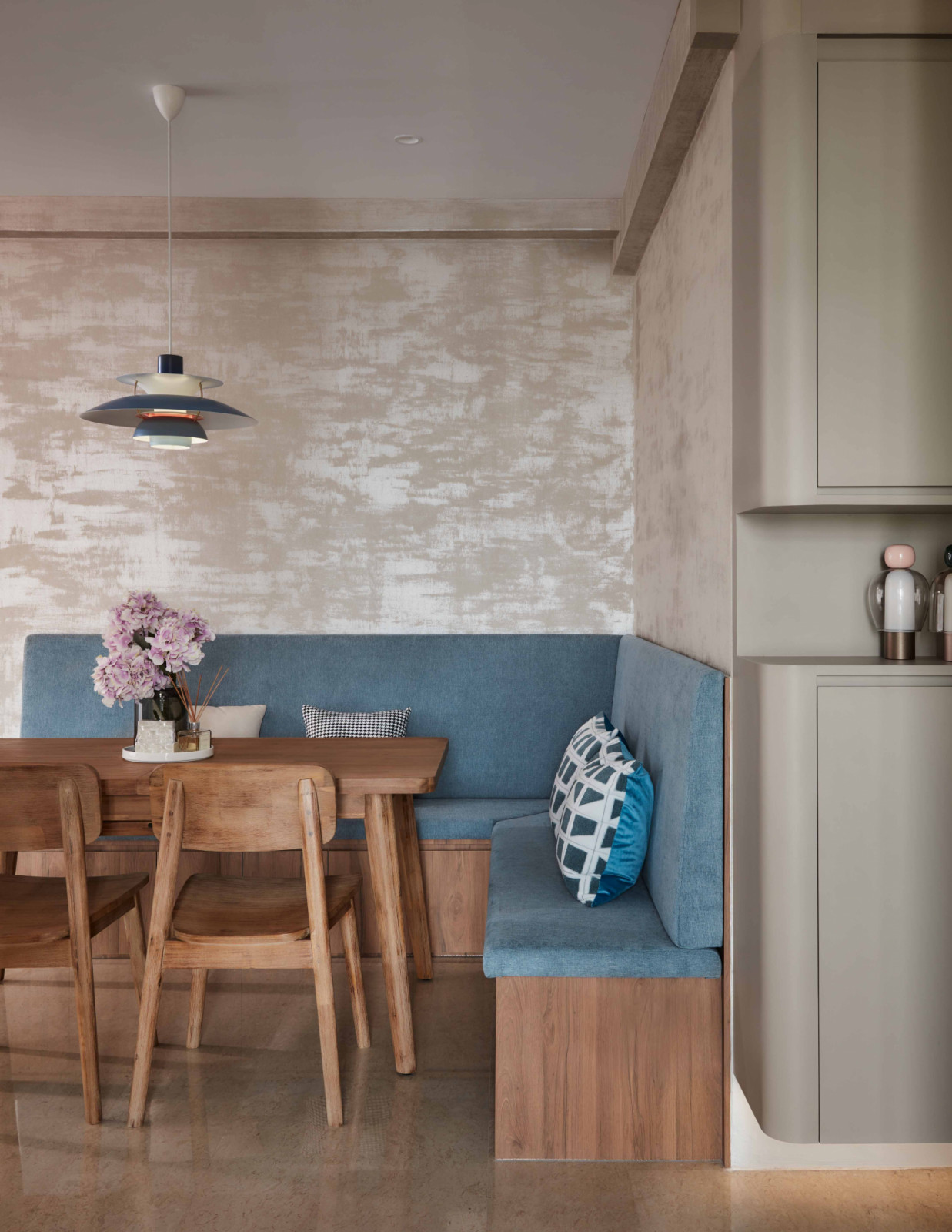 A banquette dining nook in dusty blue sits beneath a PH5 pendant, paired with solid wood furniture