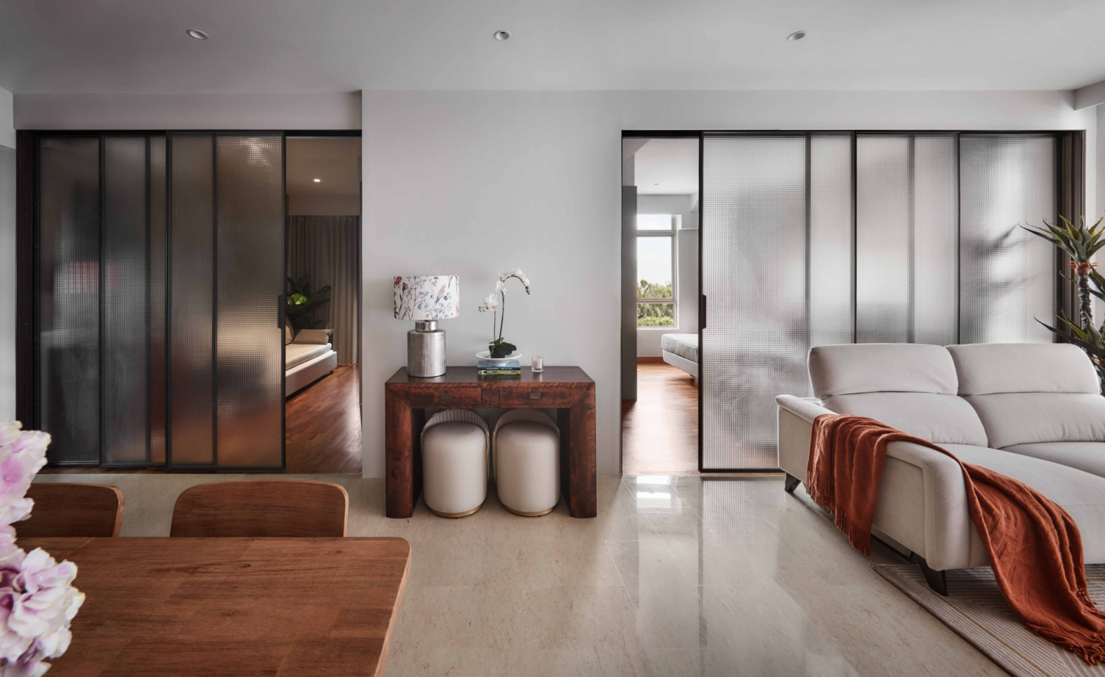Frosted glass doors and a rich wood console divide the living and dining spaces with quiet elegance