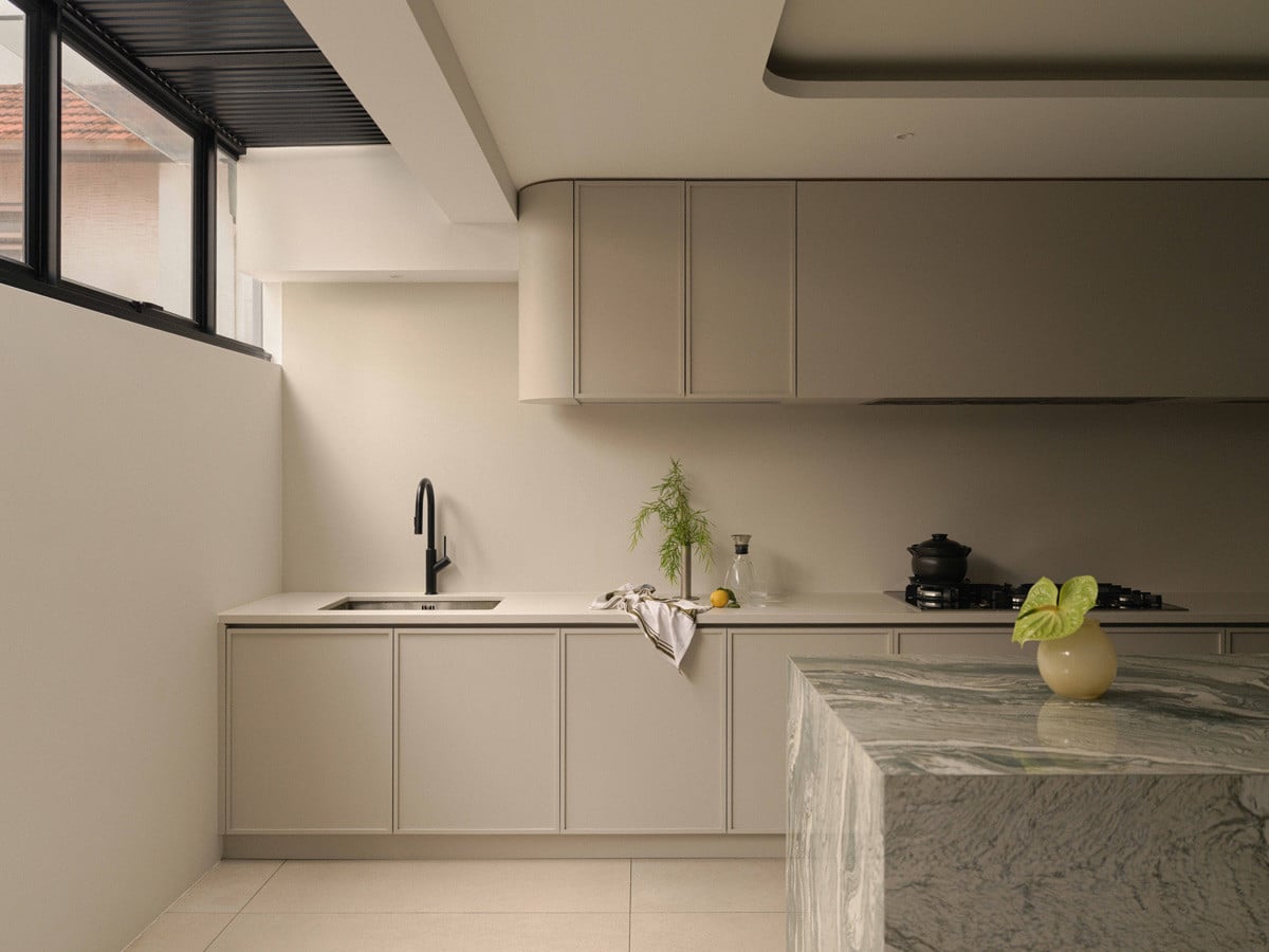 Curved cabinetry and a steel-framed clerestory window let daylight spill into the kitchen, keeping it connected to the outdoors.