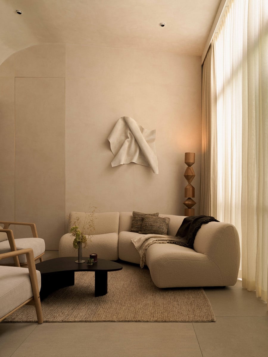 In the terrace house’s studio, a King Living 1977 curved sofa stands beneath a wall artwork from Montana Moore titled “Connections”, with a braided rug from Aratamete softening this light-filled corner