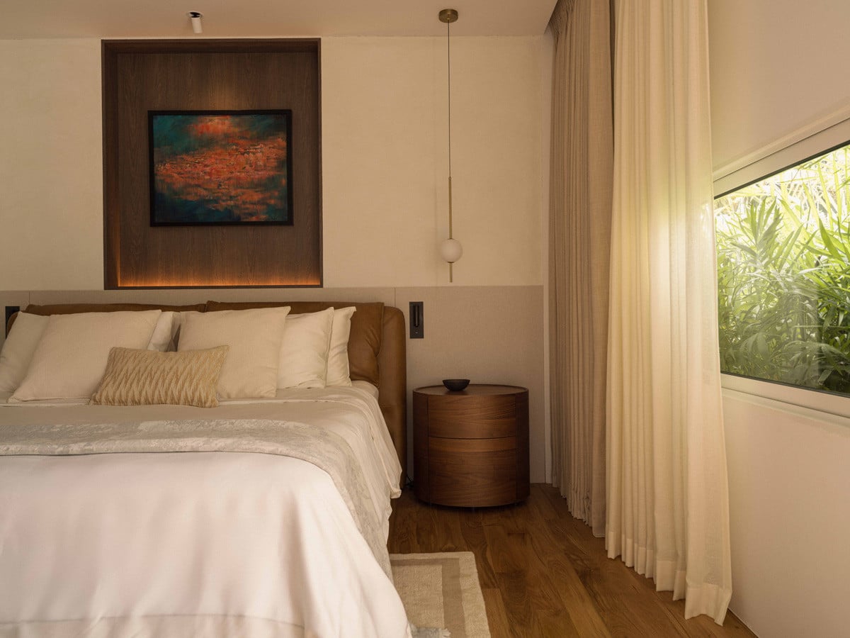 The master bedroom has a picture window to a lush garden, with artwork set into a backlit wood niche above the bed