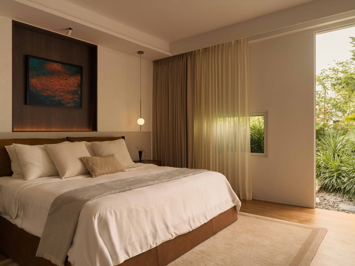 The master bedroom opens to the garden, where soft drapery, an Aratamete tencel rug and Nightworks Studio pendant lights shape a calm, intimate retreat