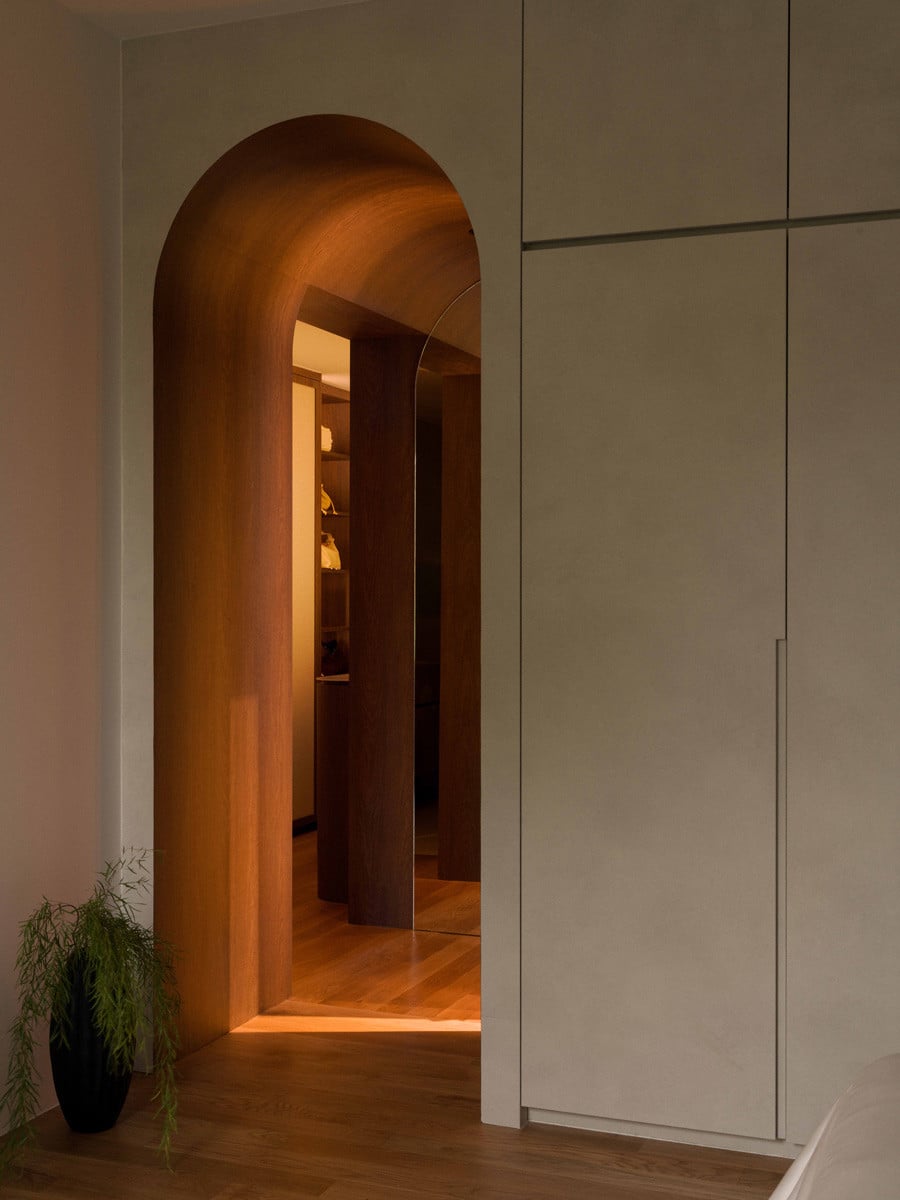 An arched, wood-clad passage leads from the master bedroom into the walk-in wardrobe