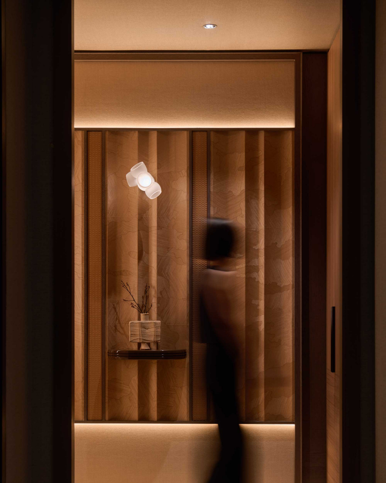 A corridor vignette pairs tone-on-tone vertical panelling with concealed lighting;