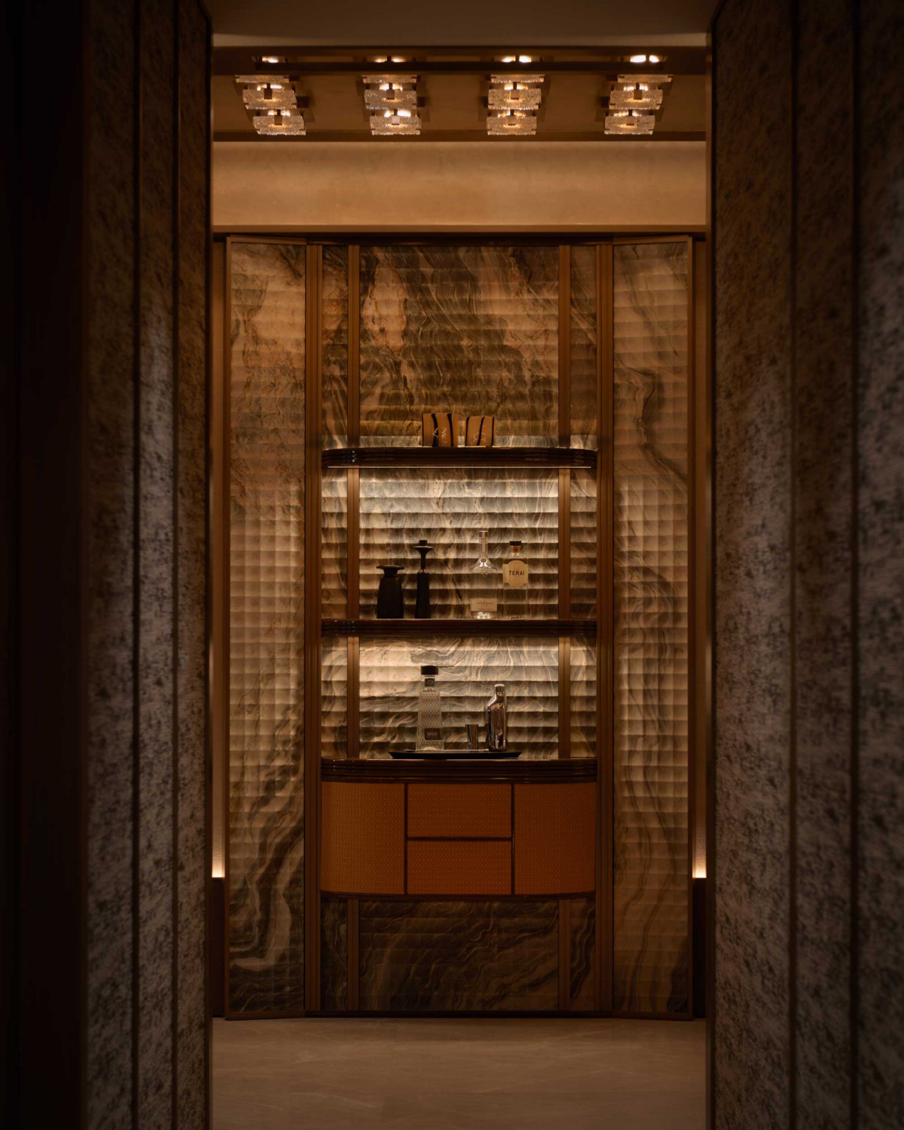 A compact bar niche is framed in marble and textured glass