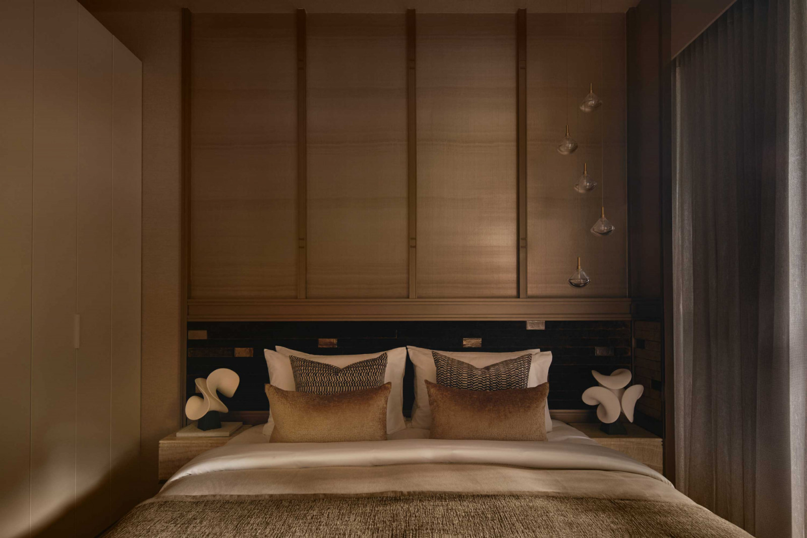 This bedroom is anchored by a padded headboard and flanked by sculptural bedside lamps