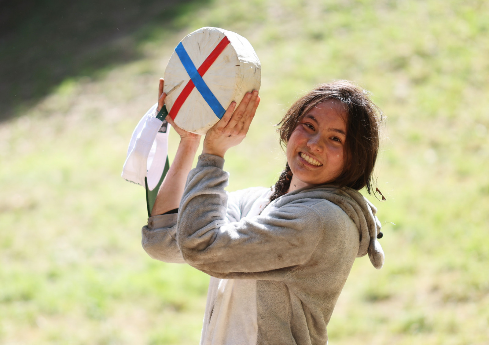 A competitor celebrates with a prized wheel of Double Gloucester at England's historic Cooper’s Hill Cheese-Rolling event, where participants race down a steep slope in pursuit of the rolling prize.  (Photo: Getty Images)
