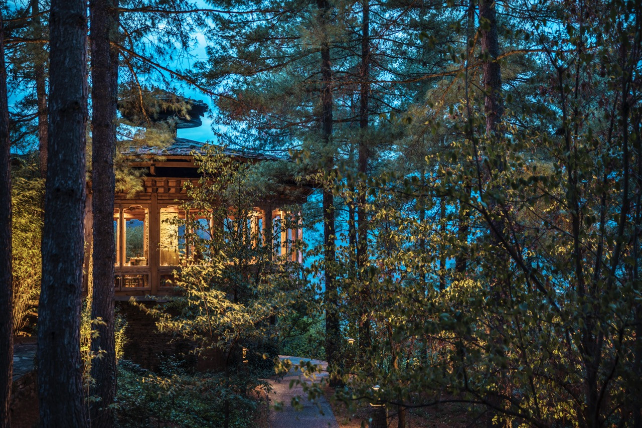 Uma Paro’s Bukhari restaurant glows through the pine trees at dusk
