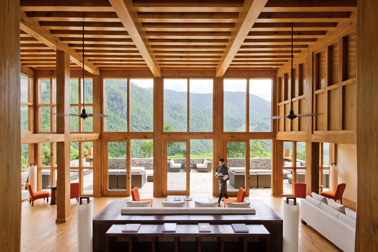 Uma Punakha’s double-height lounge pairs exposed timber framing with floor-to-ceiling windows onto the valley