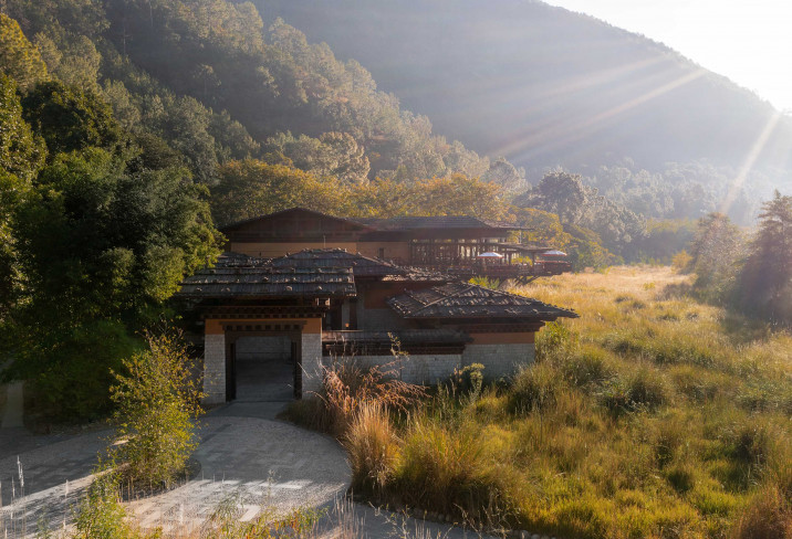 Pemako Punakha’s timber-and-stone buildings emerge from the Punakha Valley’s tall grass at sunrise