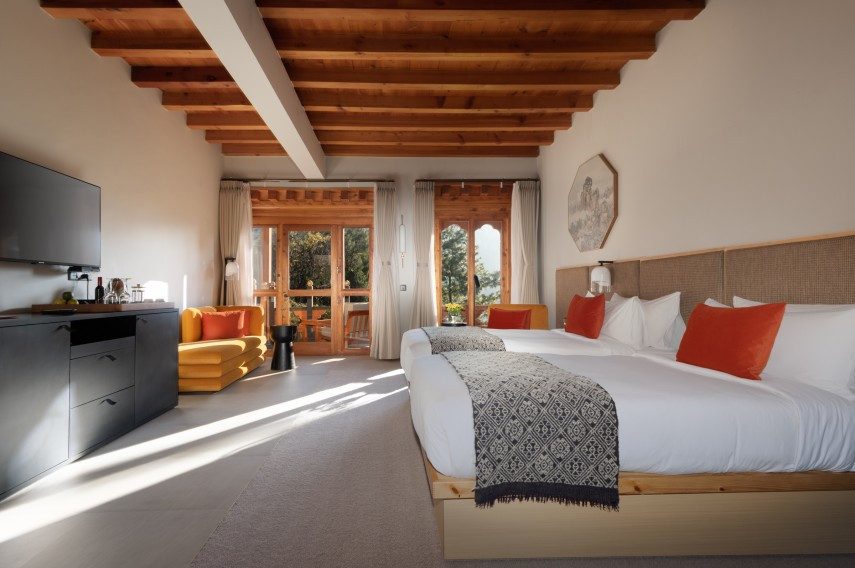 A suite at Zhiwaling Heritage combines timber-beamed ceilings with carved window surrounds and a private balcony overlooking the pines