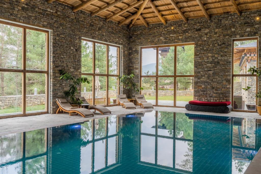 Zhiwaling Heritage’s indoor pool sits beneath a timber-beamed ceiling, framed by dry-stone walls and floor-to-ceiling windows onto the garden