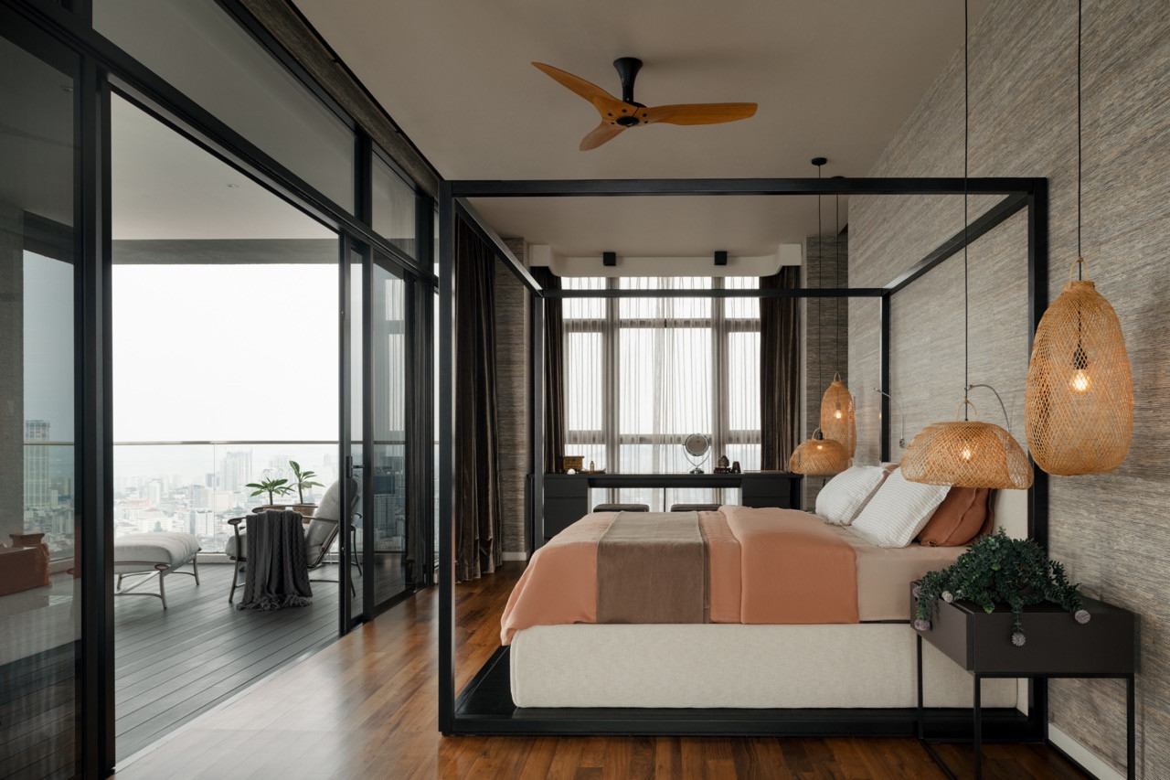 The master bedroom’s black-framed four-poster bed sits beneath clustered rattan pendants, with bamboo-textured wallpaper