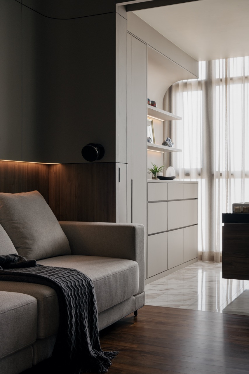 Warm timber panelling with recessed LED lighting and clean white built-in shelving define the quieter end of the entertainment room