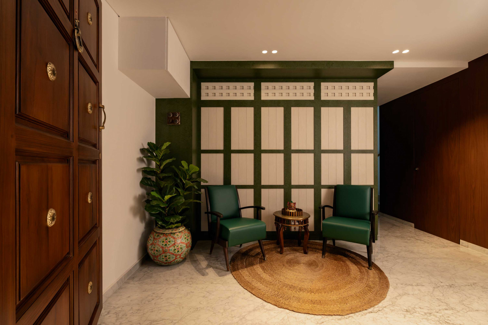 A foyer seating nook is set against a gridded panel referencing vernacular ventilation screens