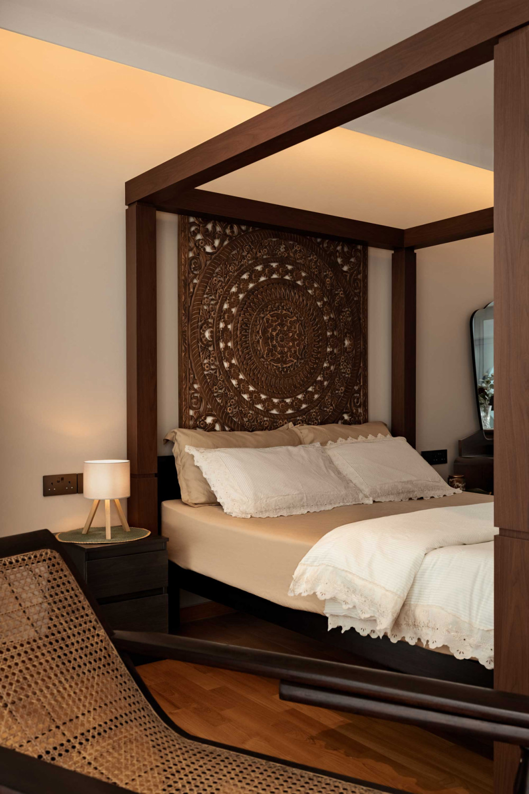 A timber carving in lieu of a headboard complements the four-poster bed