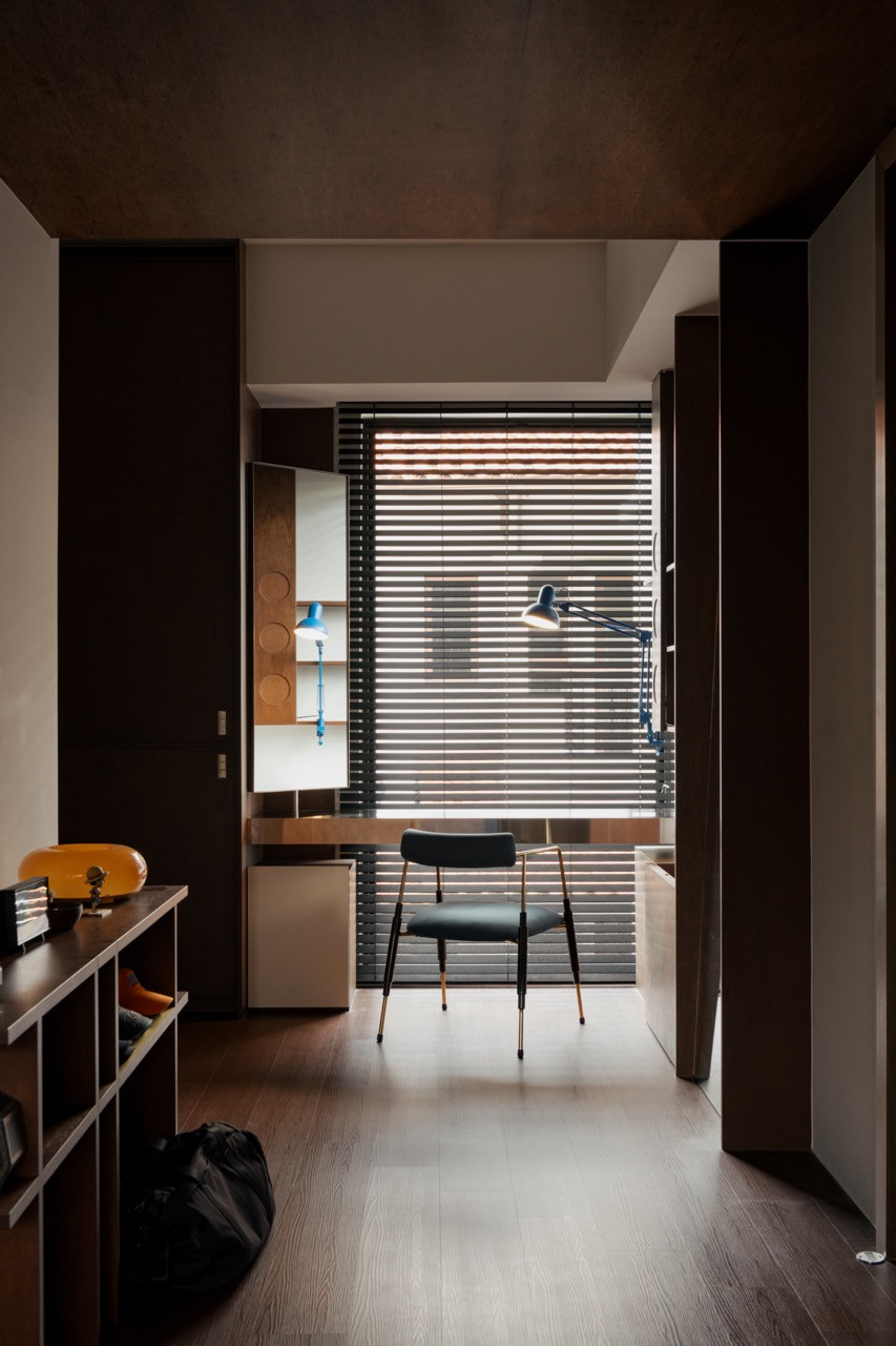 A study nook is fitted with a vintage-style desk chair and an adjustable task lamp, set beneath a timber-clad ceiling