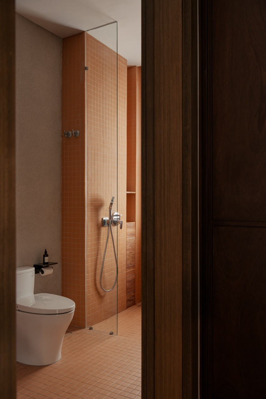 The ensuite shower is finished in terracotta-toned mosaic tile, glazed brick continuing from floor to wall