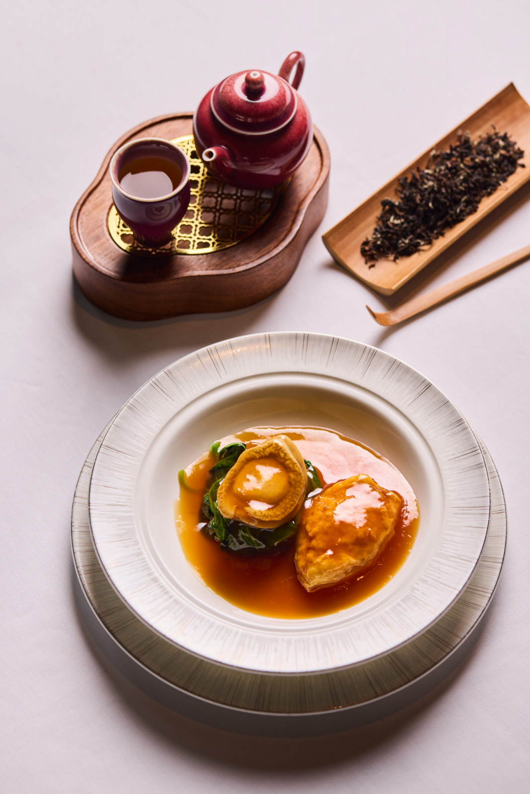 Braised South African Abalone and Chicken Puff from Lai Ching Heen, presented with a traditional Chinese tea service.