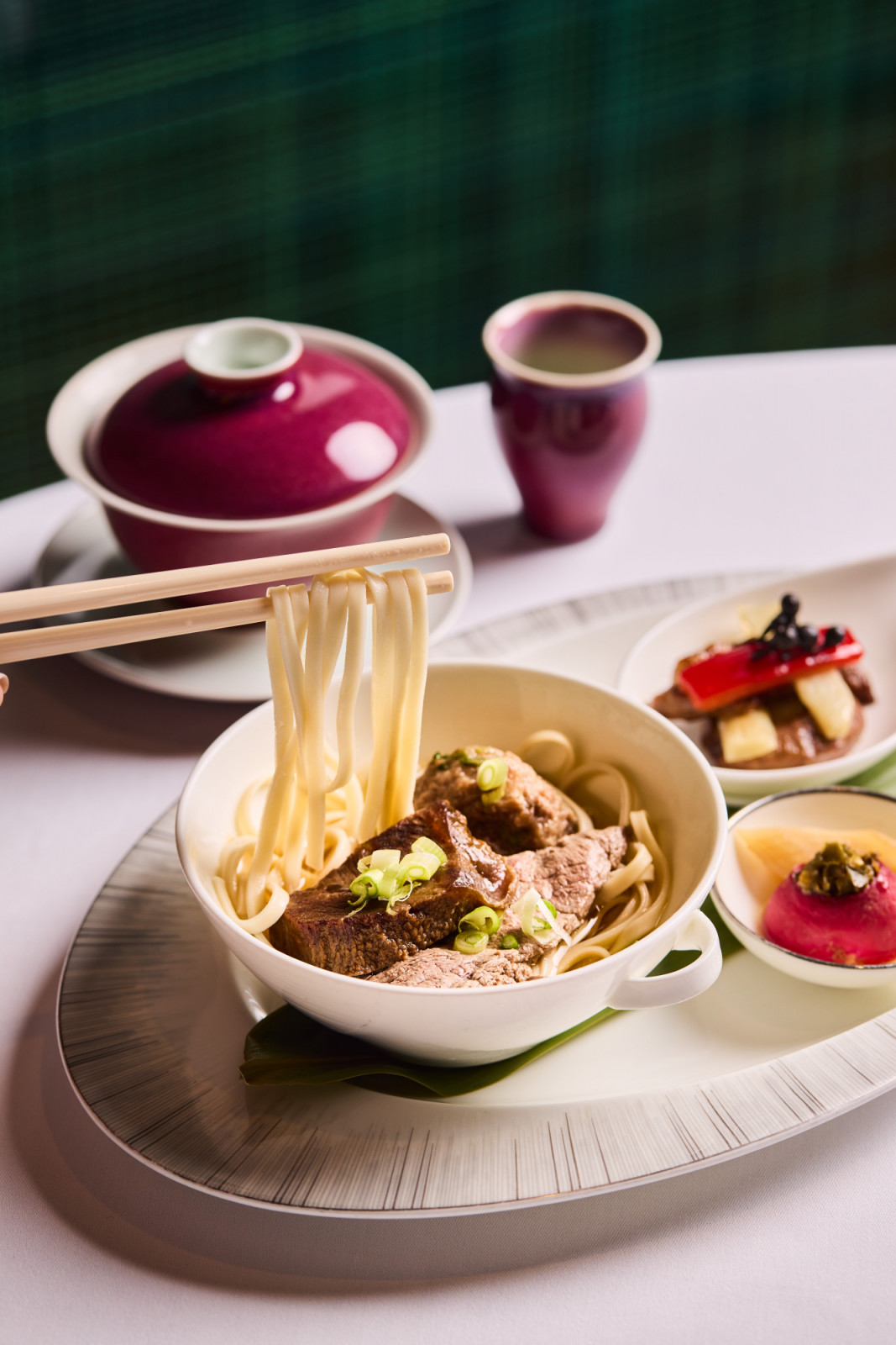 Braised Beef Brisket Noodles at Lai Ching Heen, served elegantly with gourmet side dishes and fine tea.