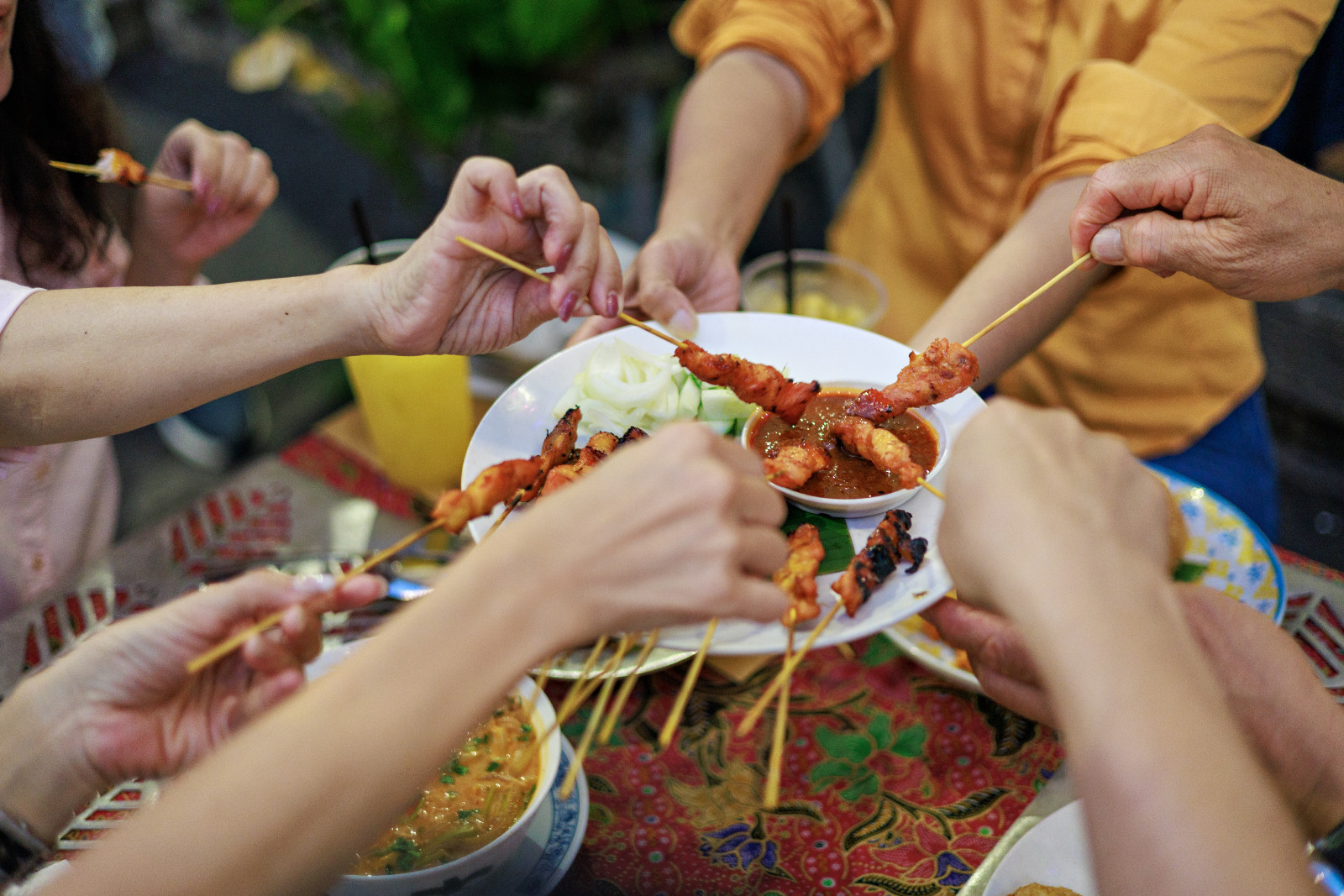 A group of mid-adult Asian friends enjoying delicious street food while exploring  in the beautiful historical city of Georgetown, Penang.
