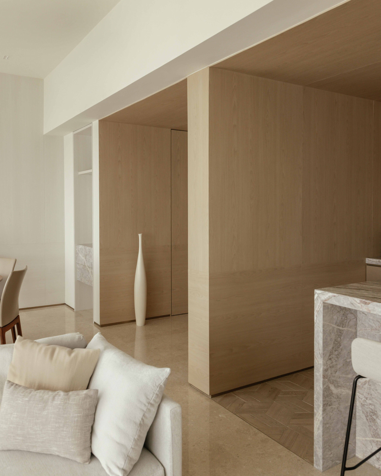 Oak millwork and a slender floor vase mark the transition between entrance and living spaces