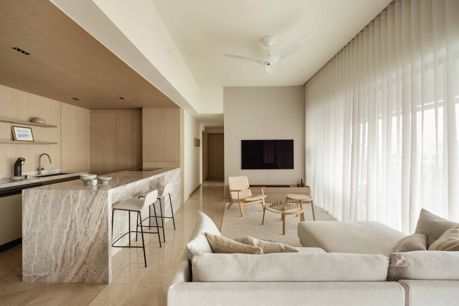 Sheer curtains soften the light across the open-plan living, dining and kitchen spaces