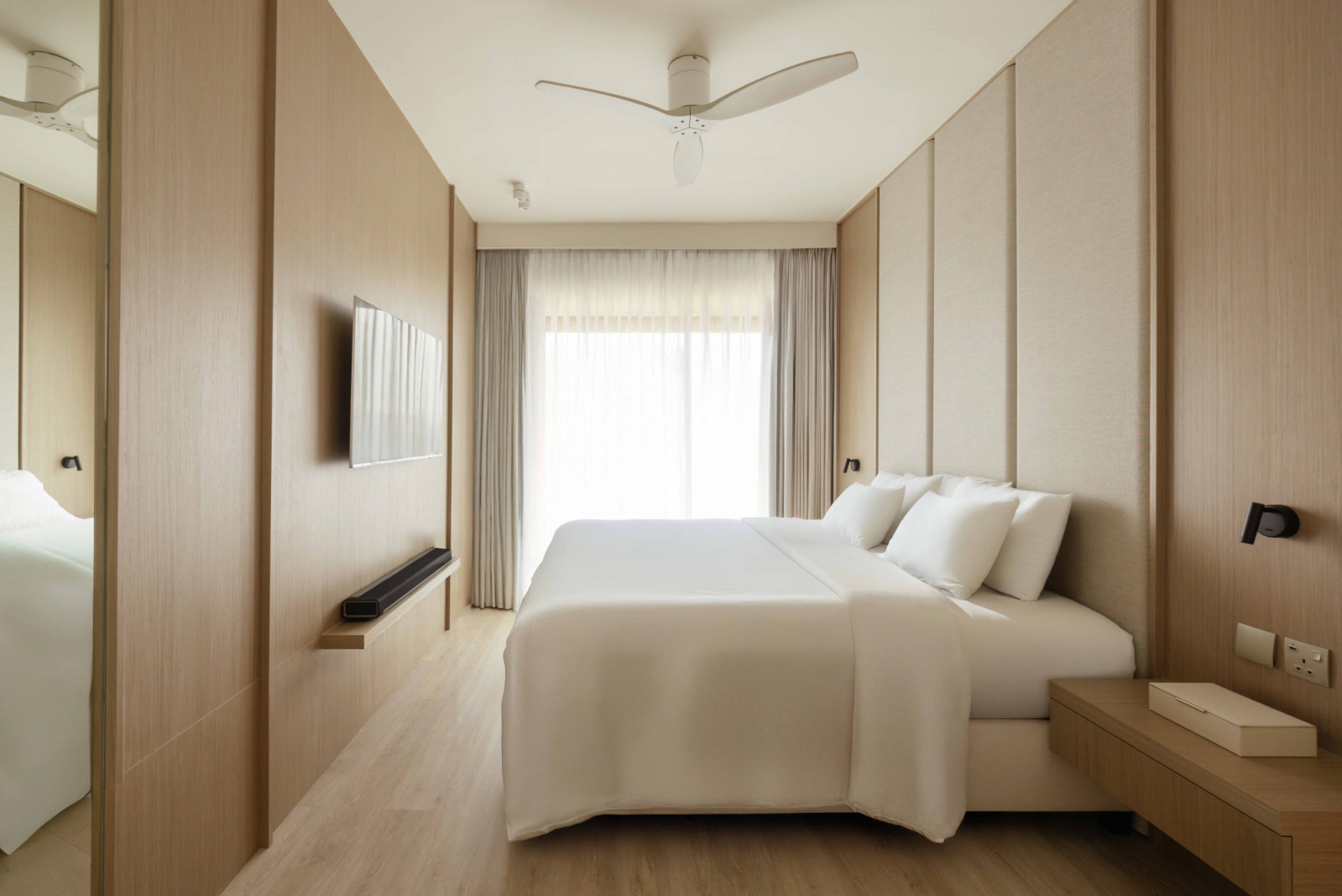Full-height panelling and soft upholstery lend the master bedroom a serene, elongated feel