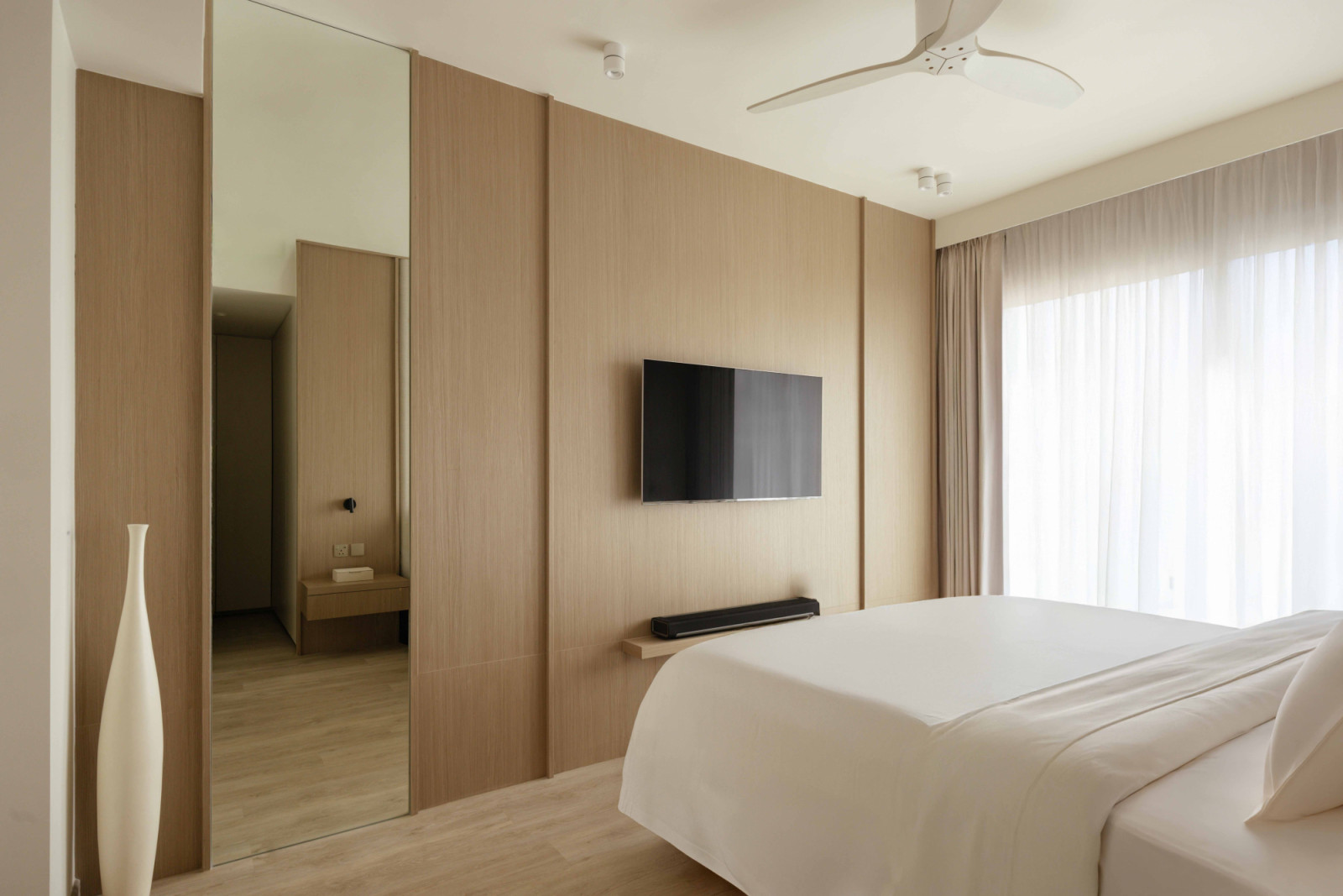 A full-length mirror and warm timber panelling extend the sense of space in the bedroom