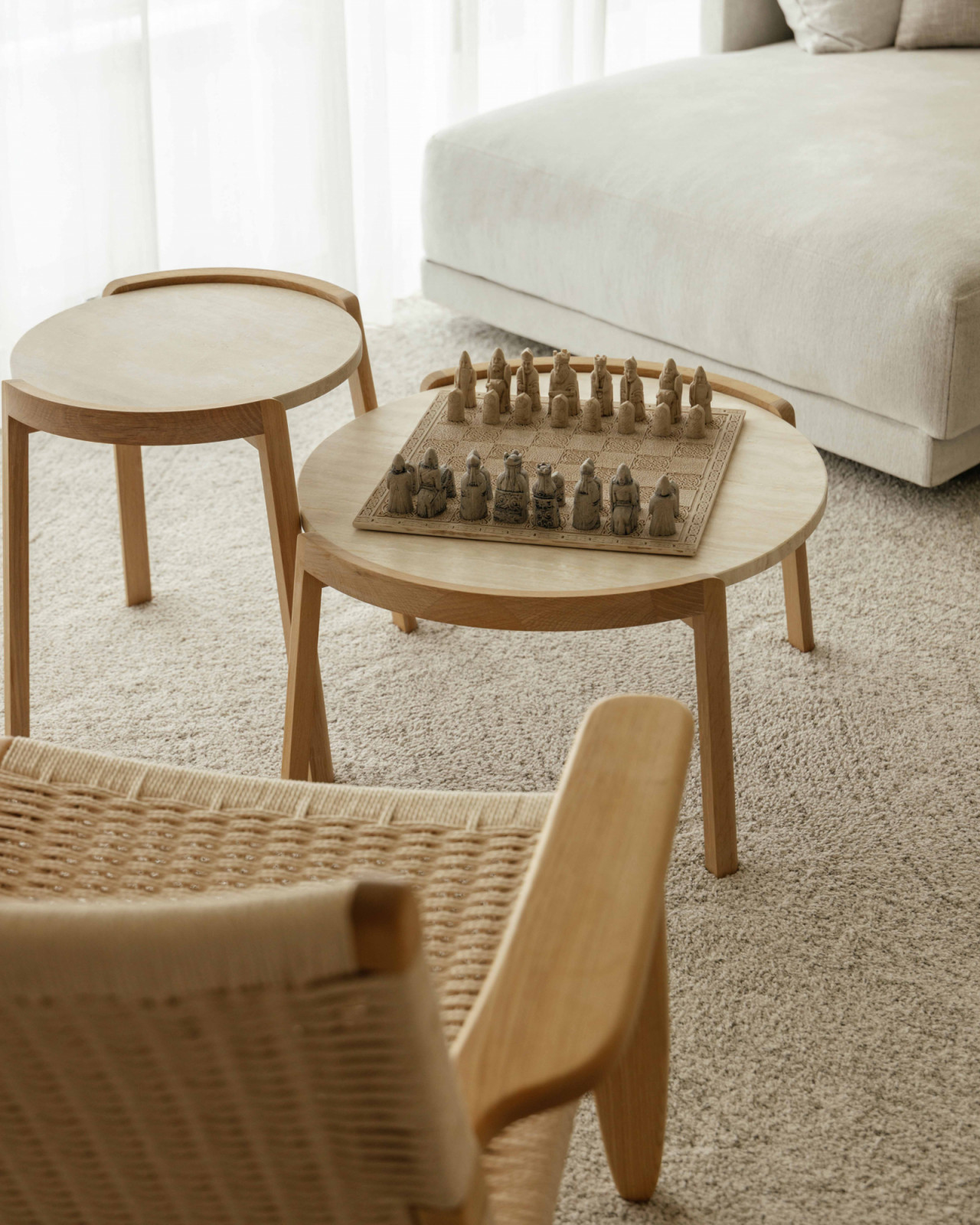 A carved chess set rests atop nested side tables in the living area