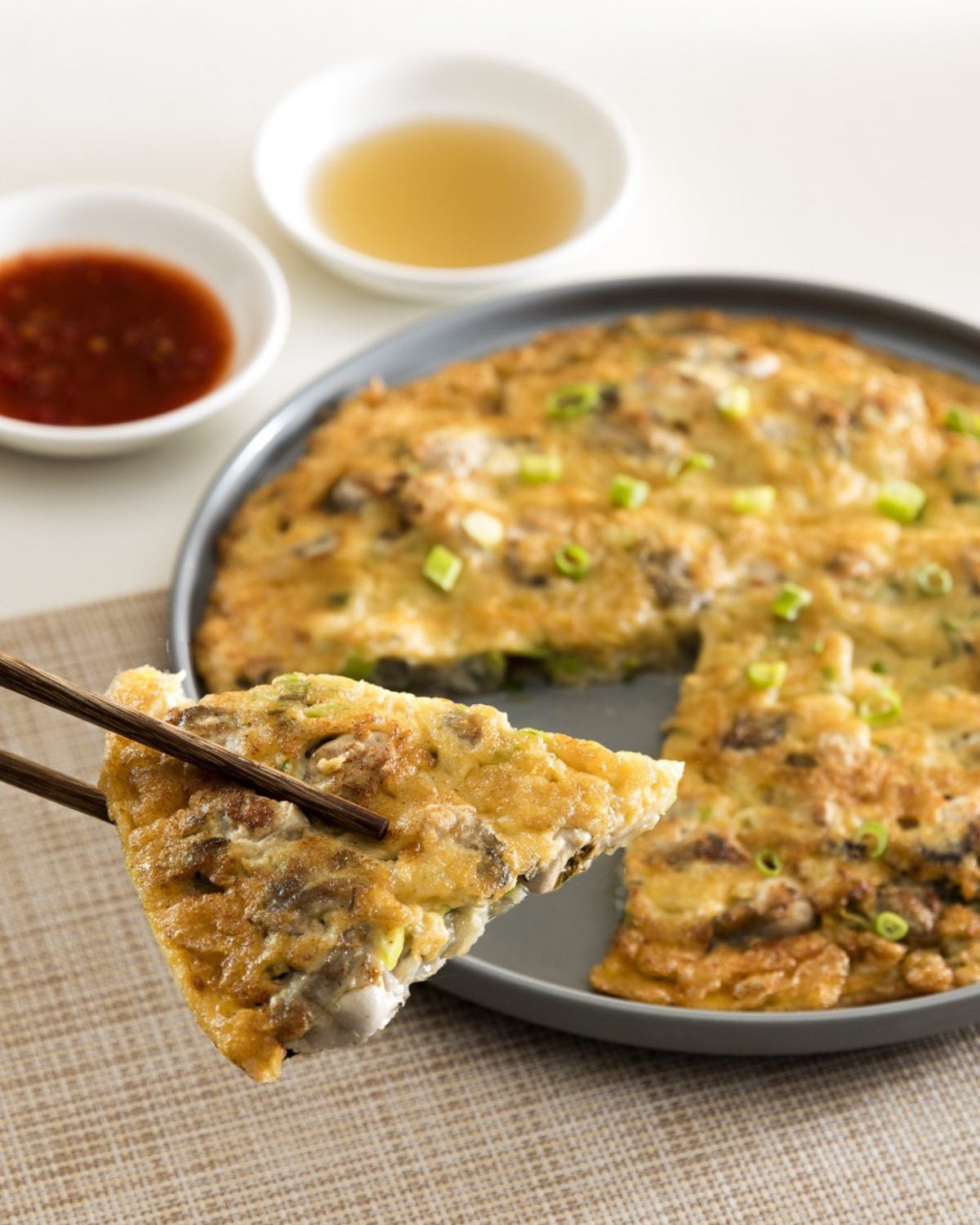 An oyster omelet, a staple of East and Southeast Asian dining, is served with accompanying sauces.
