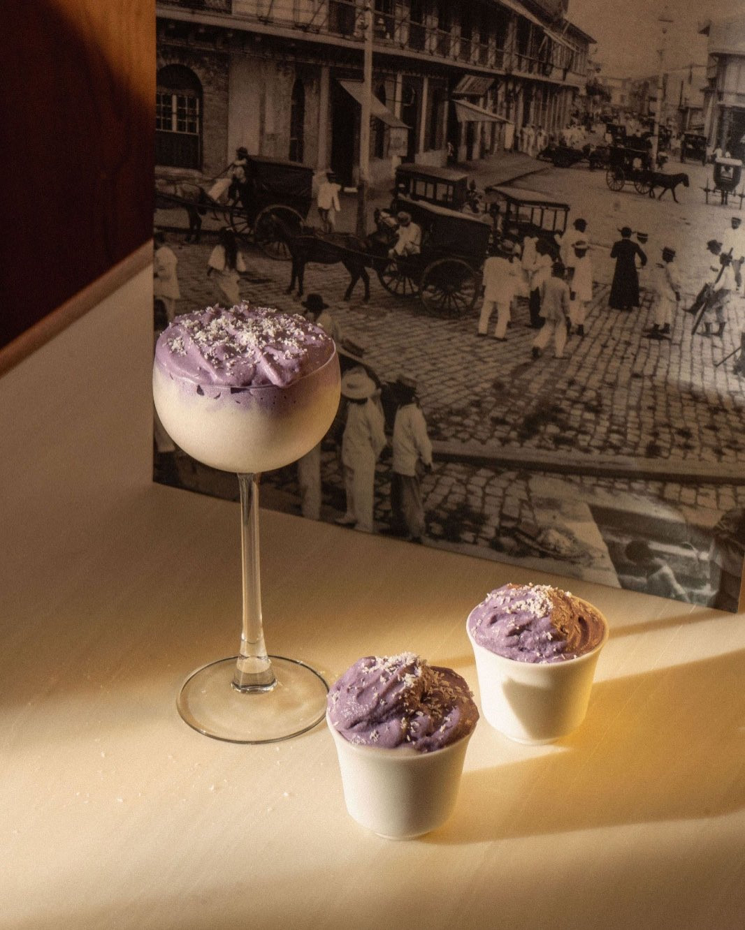 A layered purple and white drink, with two individual desserts, each adorned with white sprinkles.