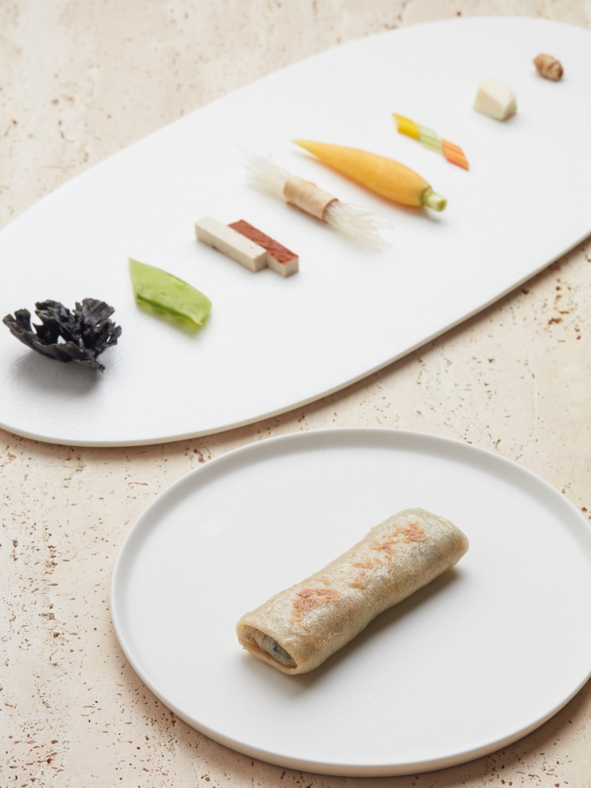 A refined savory roll is served with delicate preparations of fresh vegetables and ingredients, showcasing modern Shanghai gastronomy.