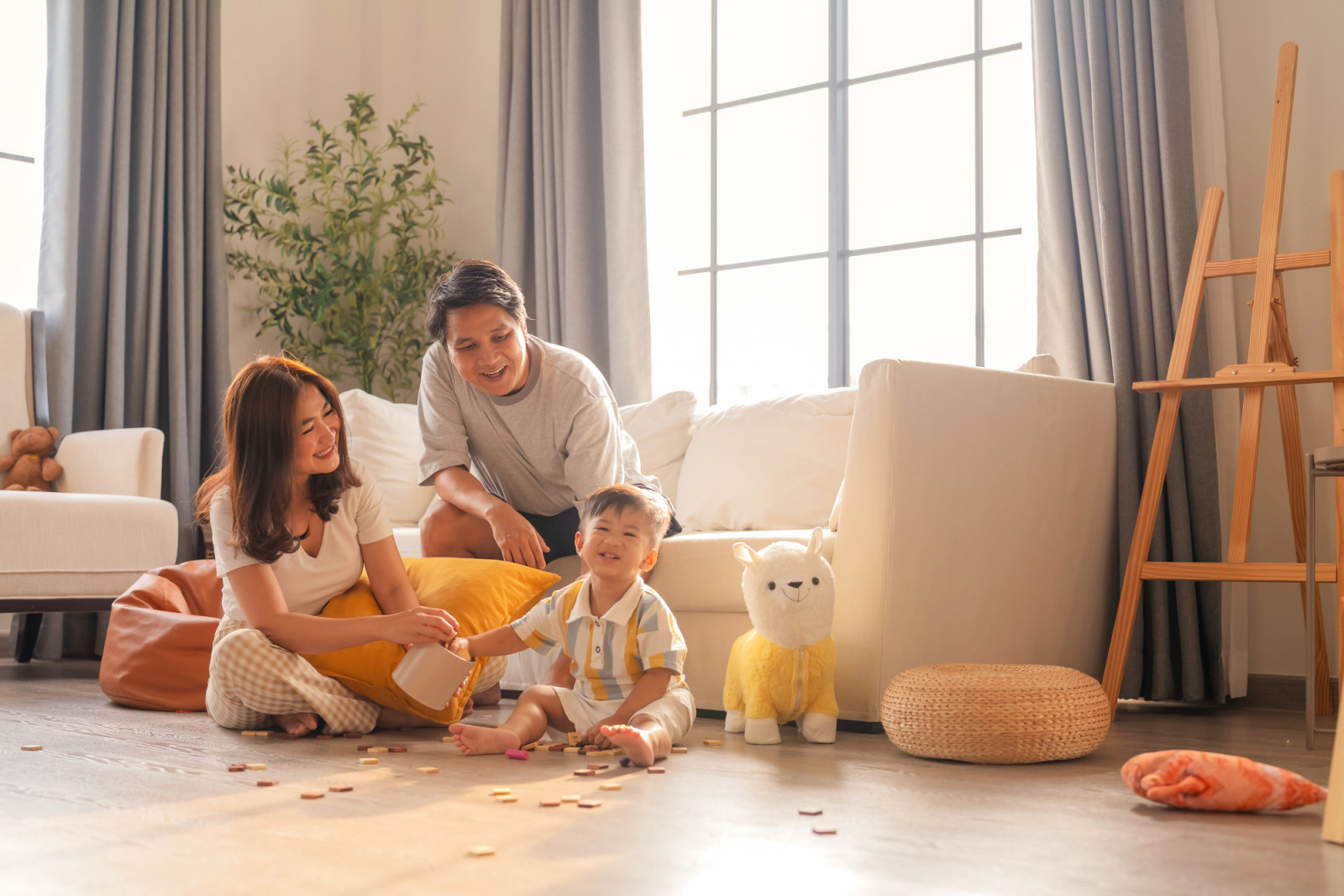 Portrait of young Asian family father mother son toddlerAsian family sitting in the living room Parents and children relax during their holiday at home Happy mother playing with cute little baby boy on a wooden floor at home