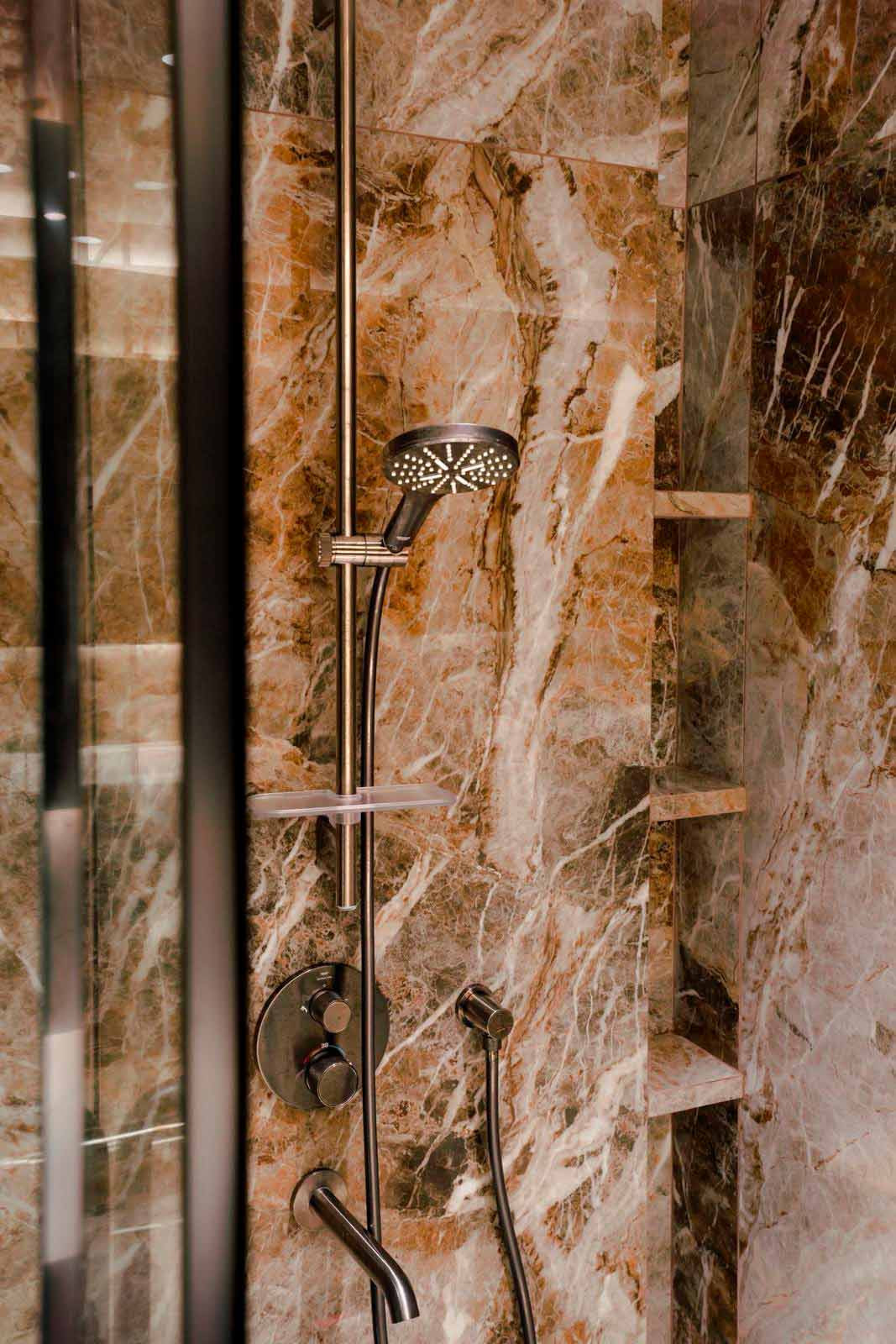Full-height marble surfaces wrap the shower