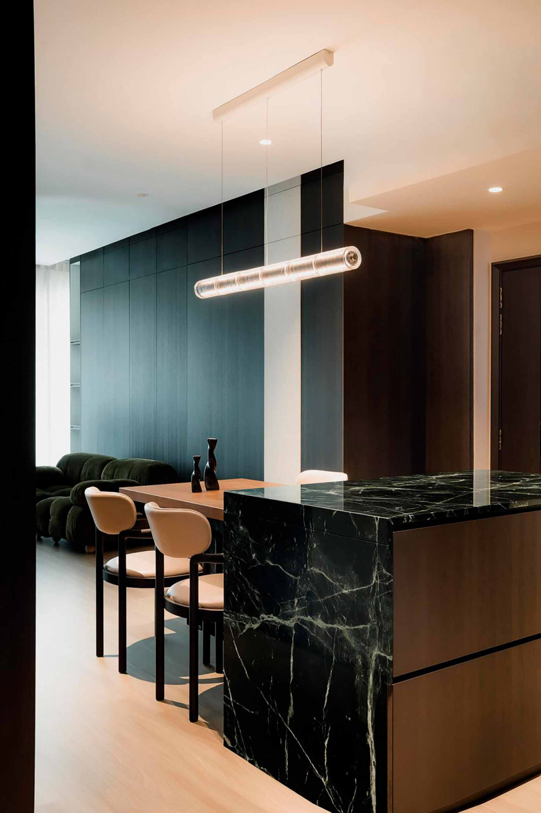 A dark green marble island with a timber dining table forms the centrepiece of the living-dining area