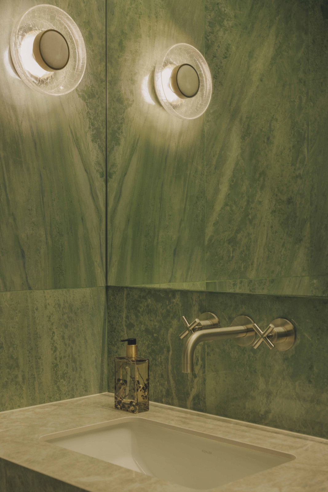 Deep green slab marble, brushed brass fittings and seasonal blooms create an exquisite powder room that deserves to be immortalised