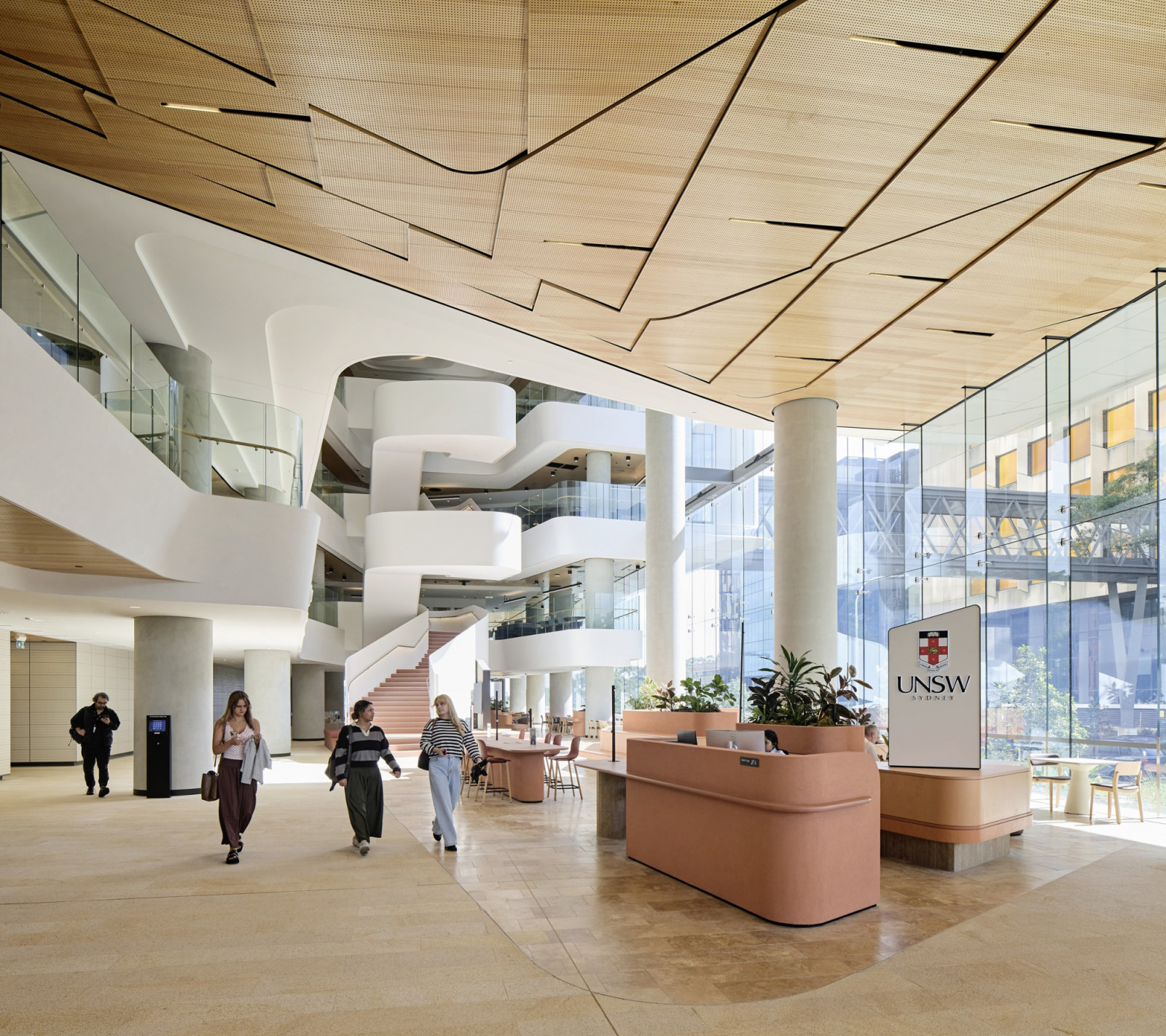 Terracotta-toned service desks and seating anchor the ground floor, set beneath a folded timber ceiling (Photo: Hufton + Crow)